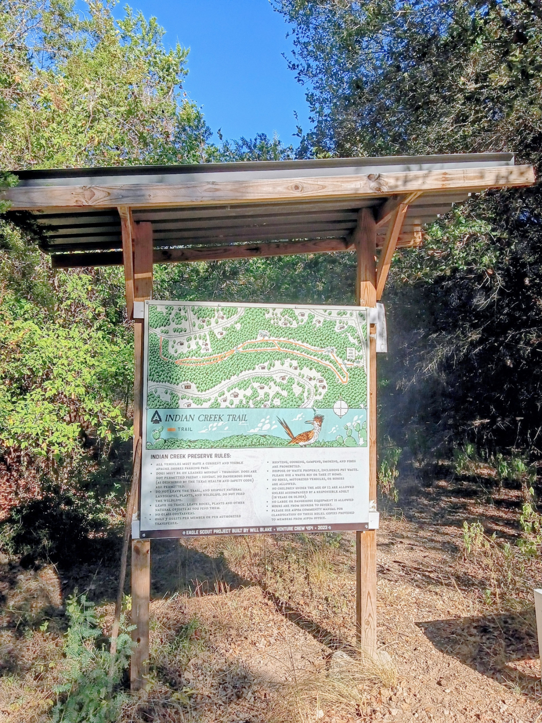 Wooden pagoda at the Indian Creek Trailhead in Apache Shores, with the trail map and information display beneath its roof and stone cairns nearby.