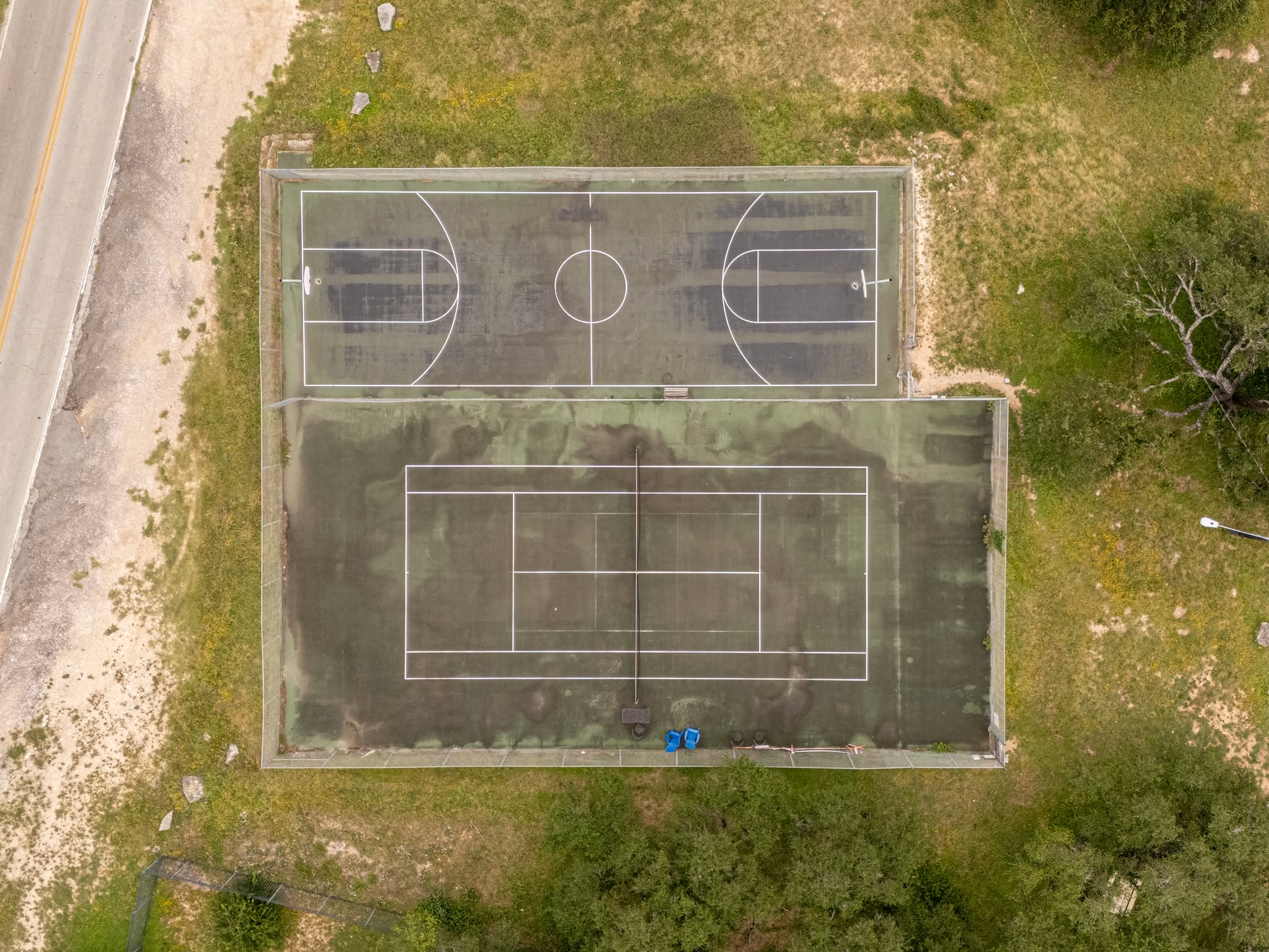 Aerial view of the Apache Shores sports courts, showing the tennis and basketball courts surrounded by mature trees and the wooded neighborhood.