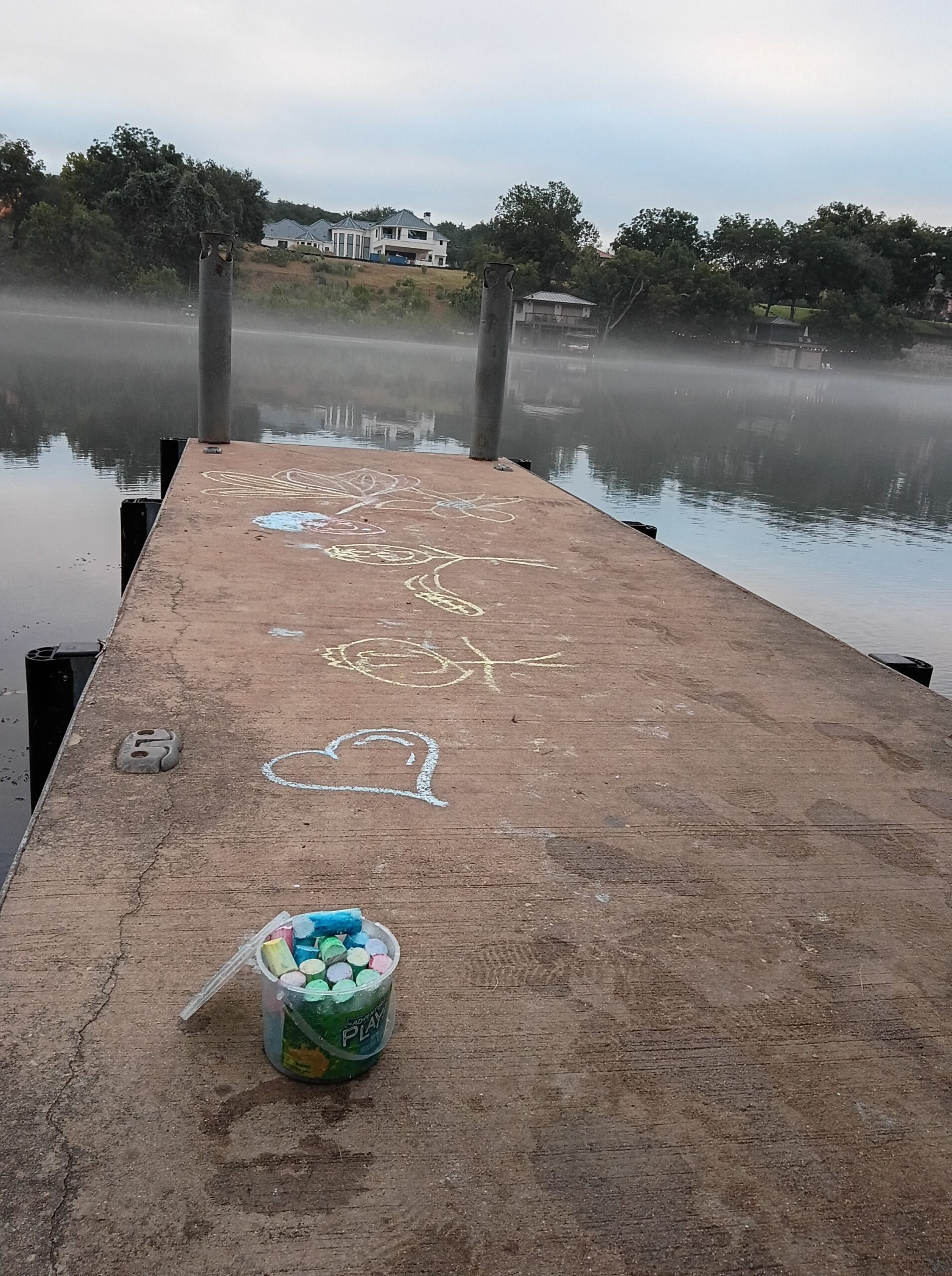 Colorful chalk drawings and messages covering the wooden dock at Lakeside Park in Apache Shores.