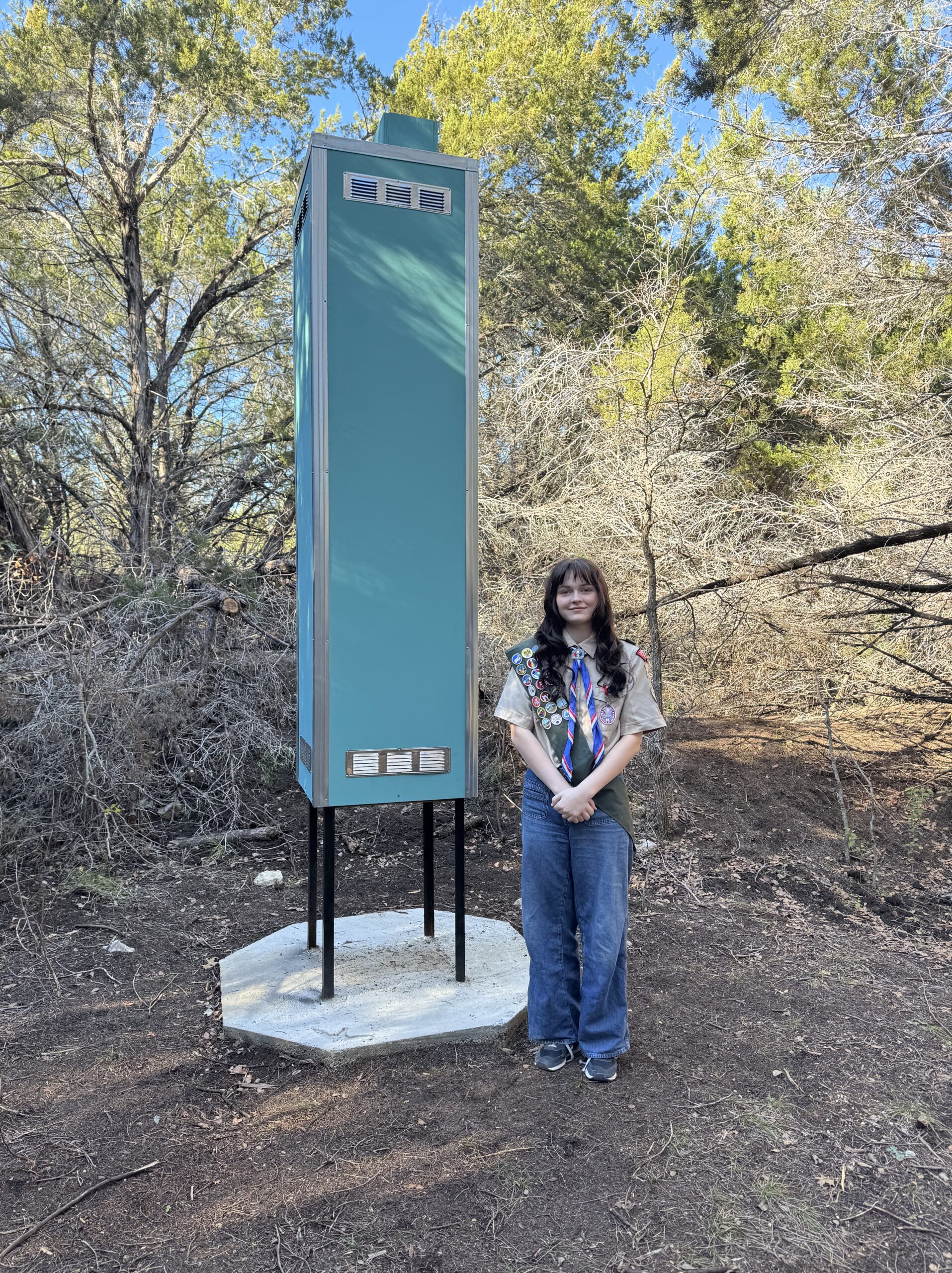 Presley Blake standing beside the tall green Chimney Swift Tower she created as an Eagle Scout project for Apache Shores POA.